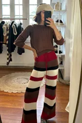 Pantalón tejido artesanalmente a rayas horizontales en tonos marrón, beige, negro y rojo.