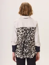 Camisa de corte clásico con frente en color beige, mangas con puños en contraste color negro y espalda con estampado animal print. Presenta cuello camisero, cierre frontal con botones y bolsillo en el pecho.