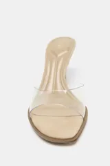 Sandalia tipo mule color beige con tira de vinilo transparente y tacón fino.