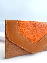 Billetera de cuero color naranja y marrón con cierre de broche y monedero externo.