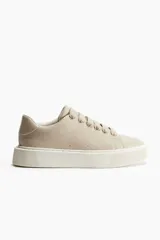 Zapatillas deportivas color beige con suela gruesa acanalada.