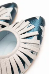 Zapato tipo blucher de cuero con acabado metalizado en color azul petróleo y estampado de estrellas blancas. Presenta un diseño con flecos decorativos en la parte frontal, cierre con cordones y suela plana de cuero.