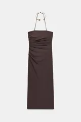 Vestido midi de color marrón con escote recto y cuello halter que incorpora una aplicación metálica tipo choker. Presenta tirantes finos, detalle de frunces laterales en el delantero, abertura en la espalda y cierre con cremallera oculta.
