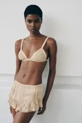 Shorts satinados color beige, con tiro medio, cintura elástica y diseño fluido. Presentan bordados florales en los laterales y volantes con puntillas en el bajo.