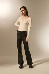 Pantalon de eco-cuero negro, de corte flare con costuras verticales frontales y detalle de tajo en el ruedo.