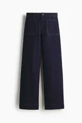 Pantalón de jean color azul marino, de tiro alto y corte wide leg, con amplios bolsillos frontales de parche y presillas para cinturón.