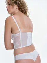 Corset de encaje blanco con copas con aro sin relleno, cuerpo con ballenas para estructura y breteles ajustables. Presenta cierre posterior con ganchos y diseño entallado.