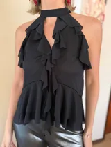 Blusa color marrón chocolate con escote halter, diseño sin mangas y múltiples volados verticales y horizontales que aportan volumen y movimiento.