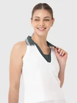 Top deportivo sin mangas con cuello polo, diseño tipo crop y escote en V. Presenta un diseño bicolor con cuerpo blanco y detalles en cuello y solapa en color verde oscuro.