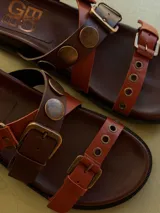 Sandalias de cuero marrón, con diseño de triple tira con hebillas, detalles de tachas y apliques de pelo con estampado animal print.