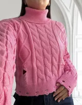 Sweater rosado de punto con cuello alto, mangas largas y diseño con roturas.