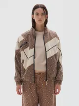 Campera de estilo deportivo con cierre frontal, confeccionada en denim con estampado de rombos en tonos marrones y paneles en color crudo. Presenta cuello alto, puños y cintura elásticos, y detalle de etiqueta con logo en el pecho.