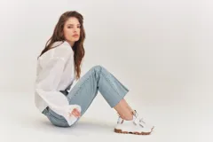 Championes de estilo urbano en color blanco con detalles en tono arena. Presentan un diseño con doble tira de velcro en el empeine, suela de plataforma dentada en color caramelo y tirador en el talón.