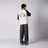 Remera de jersey de algodón con diseño bicolor, cuerpo en color crudo y mangas raglán en azul marino. Presenta escote redondo de ribb y un pequeño estampado gráfico en el centro del pecho.