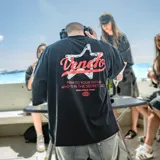 Remera negra de algodón con efecto gastado, corte oversize y estampado en la espalda con una estrella y la palabra "Venefo" en rojo.