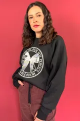 Buzo negro de friza de algodón con cuello redondo y puños y ruedo acanalados. Estampa circular en el frente con la frase "Be real not perfect" y el nombre de la marca.