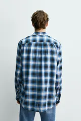 Camisa de corte regular fit confeccionada en tejido fluido de algodón y viscosa. Presenta un diseño de cuadros, cuello solapa, manga larga con puños abotonados, bolsillo en el pecho y cierre frontal con botones.