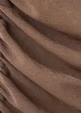 Vestido corto marrón con efecto de doble prenda, superpuesto sobre un fondo negro. Presenta tirantes finos y un diseño ajustado al cuerpo con fruncidos en los laterales.