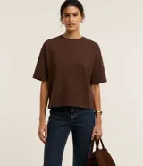 Blusa básica de mujer color negro, confeccionada en malla encorpada de algodón, con cuello redondo y mangas cortas de corte oversized con sisas desplazadas.