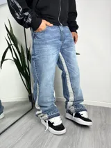 Pantalón de jean estilo baggy, color celeste lavado, con paneles laterales en tono más claro y diseño acampanado.