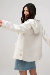 Campera liviana con capucha, de corte clásico, color beige, con bolsillos laterales con solapa y cierre frontal.