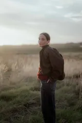 Campera tipo bomber color marrón oscuro, con cierre frontal, cuello redondo y diseño holgado.