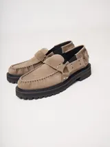 Mocasines Mutma Gales de cuero color tostado, con plataforma gruesa dentada, detalles de tachas metálicas, argollas y tira lateral con hebilla.