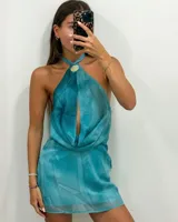 Vestido corto turquesa con escote halter y detalle de argolla dorada en el cuello, confeccionado en tejido ligero y fluido con efecto degradado.