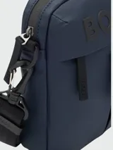 Bandolera Boss modelo Stormy, color azul marino, con logo de la marca en relieve en la parte frontal. Cuenta con compartimento principal con cierre, bolsillo frontal con cierre, correa ajustable y desmontable, y detalles de marca en los tiradores y herrajes.
