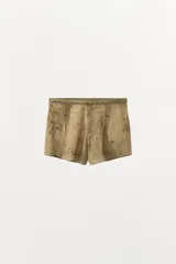Shorts de tiro bajo con cintura elástica y detalle de pliegues en el delantero. Presenta un diseño estampado con motivos florales en tonos tierra.