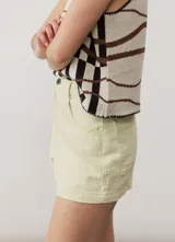 Short gris claro de tiro alto con costuras pespunteadas en contraste y bolsillos traseros amplios. Presenta una etiqueta de cuero rojo en la parte posterior de la cintura.