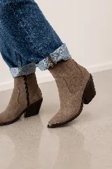 Bota corta de cuero vacuno color marrón topo, con diseño de estilo western, taco cuadrado de 7 cm y puntera metálica decorativa. Cuenta con cierre lateral interno para facilitar el calce.