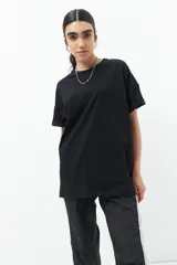 Remera blanca de algodón, corte oversized y manga corta, con cuello redondo y detalle de tres botones metálicos en cada lateral inferior.