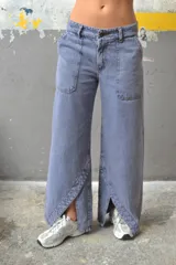 Pantalón de jean color crudo, de corte palazzo con aberturas en el ruedo y bolsillos laterales.