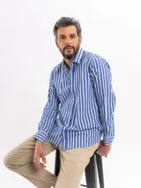 Camisa de manga larga con estampado de rayas verticales en azul y blanco, cuello clásico y cierre frontal de botones.
