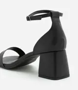 Sandalias negras de cuero sintético, con punta cuadrada, tira fina sobre los dedos, pulsera con hebilla al tobillo y tacón geométrico bajo.