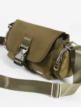 Bandolera de tela color verde militar, con tapa frontal y hebilla metálica. Cuenta con correa regulable y bolsillos laterales con cierre.