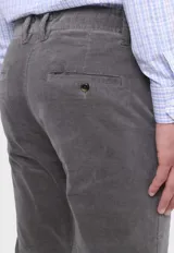 Pantalón de pana gris con corte slim fit, bolsillos laterales y traseros, y cinturón trenzado verde.