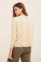 Sweater beige de punto con diseño de flores bordadas en tonos celestes y verdes en el frente, de cuello redondo y manga larga.