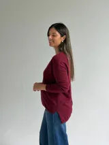 Sweater de punto en color bordó, con escote en V, mangas largas y diseño de corte recto con dobladillo ligeramente más largo en la parte posterior.