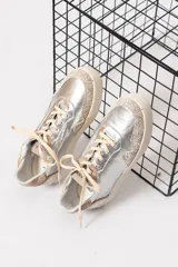 Championes plateados de cuero, con detalles en beige y suela color crema.