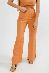 Pantalón de tiro alto con corte flare, confeccionado en lino color naranja. Presenta costuras verticales frontales que estilizan la silueta.