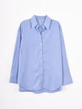 Camisa de corte oversize con estampado de rayas verticales en tonos azul y blanco, cuello clásico y cierre frontal con botones.