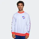 Buzo de cuello redondo color blanco con detalles en rojo y azul. Presenta el escudo del Club Nacional de Football en el pecho, bandas laterales con los colores del club en las mangas y puños y ruedo en color rojo.