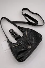 Cartera de hombro de tamaño compacto con acabado texturizado efecto cuero desgastado. Presenta un diseño con cierre superior, bolsillos frontales con cierre y una solapa central decorativa con hebilla metálica. Incluye asa fija para llevar al hombro.