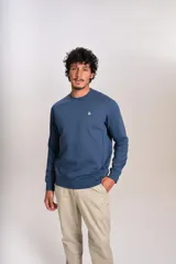 Buzo de cuello redondo en color azul, con mangas largas y puños acanalados. Presenta un pequeño logo bordado en el pecho.