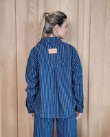 Sobrecamisa de denim con diseño de rayas verticales en tonos azules. Presenta cuello clásico, cierre frontal con botones y bolsillos delanteros de parche.