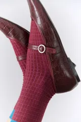 Ballerinas color borgoña con estampado croco, punta redondeada y tira sobre el empeine con hebilla metálica.