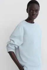 Buzo de corte oversized con cuello redondo, hombros caídos y puños y bajo acanalados. Presenta un diseño liso con interior cepillado suave.