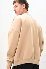 Buzo color beige de corte holgado, con cuello redondo y mangas largas.